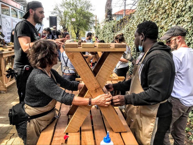 A group of people lifting up a wooden park table