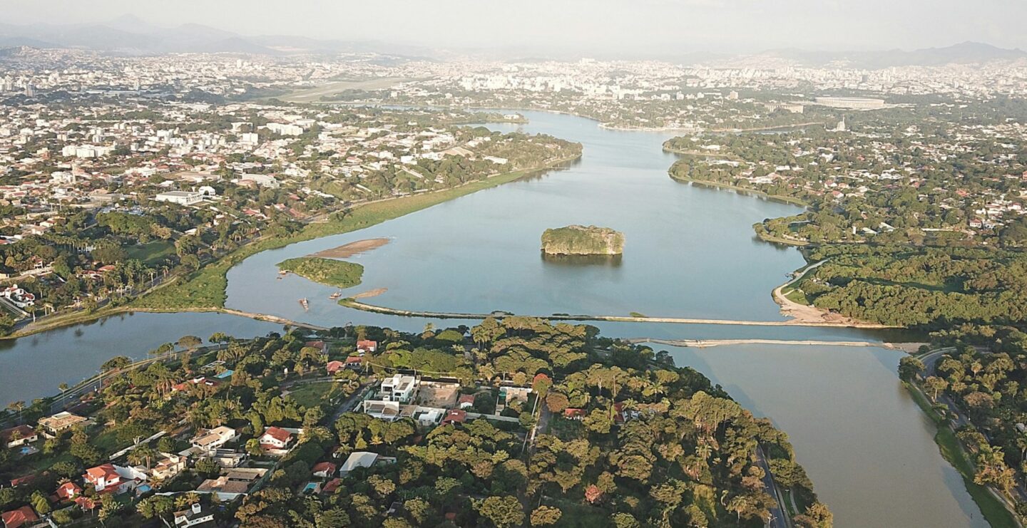 A body of water surrounded by three distinct areas of land with trees and buildings.