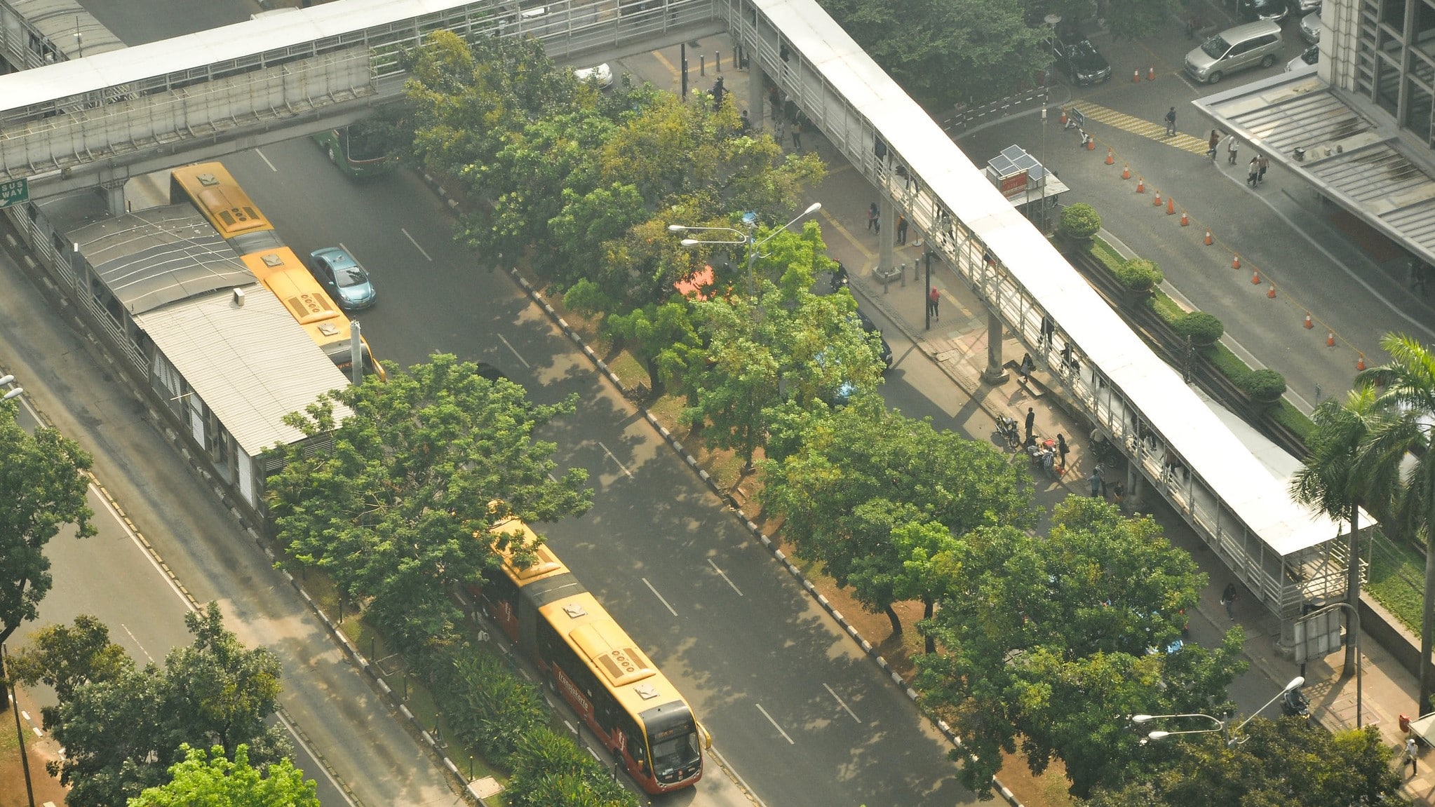 An aerial view of a bus depot lined with trees.